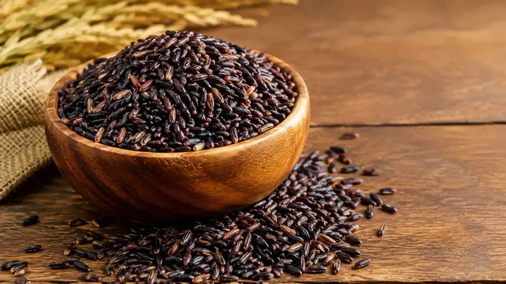 Raw Karuppu Kavuni black rice grains from Tamil Nadu displayed in a traditional wooden bowl in UAE.